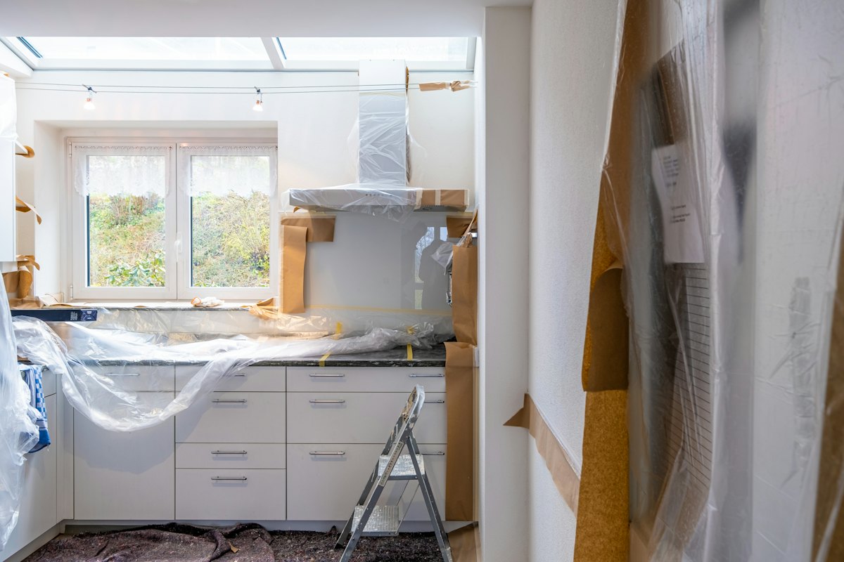 Een keuken tijdens de werken, met kasten afgedekt in plastic